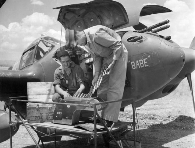 1st Lt H. A. Blood examines ammunition for the single 20 mm M2 in the nose of a Lockheed P-38 Lightning
