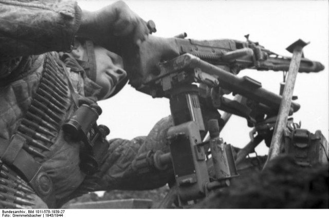 A German paratrooper puts his MG-42 heavy machine gun on a mount.