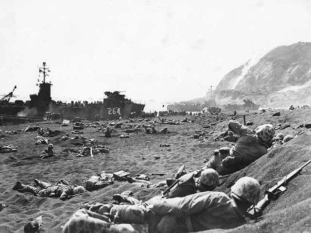 Members of the 1st Battalion 23rd Marines burrow in the volcanic sand on Yellow Beach 1. A beached LCI is visible upper left with Mount Suribachi upper right.
