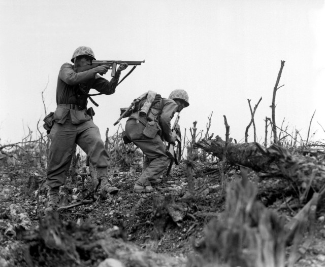 A Marine of the 1st Marine Division draws a bead on a Japanese sniper with his tommy-gun as his companion ducks for cover. The division is working to take Wana Ridge before the town of Shuri. Okinawa, 1945. S.Sgt. Walter F. Kleine. (Marine Corps) Exact Date Shot Unknown NARA FILE #: 127-N-123170 WAR & CONFLICT BOOK #: 1228