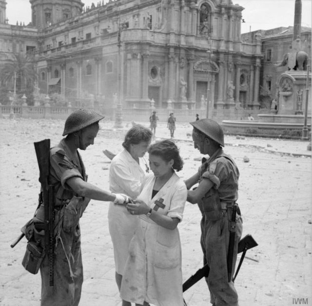 Italian nurses dress the minor wounds of two British soldiers in Catania, 5 August 1943. © IWM (NA 5341)