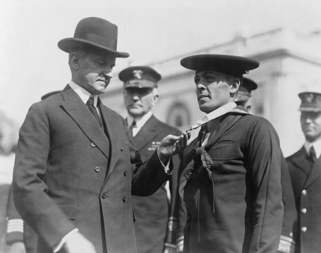 Henry Breault (center) receives the Medal of Honor from President Calvin Coolidge (Wikipedia / Public Domain)