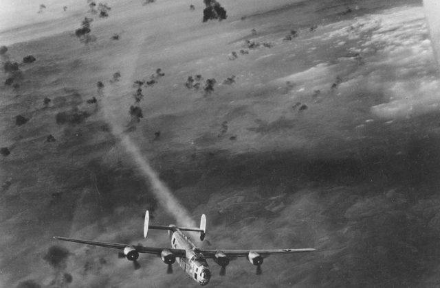 A B-24 bomber emerges from a cloud of flak with its no. 2 engine smoking (Wikipedia / Public Domain)