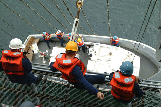 Sailors aboard the USS Essex (LHD-2) raising their captain's gig in August 2002