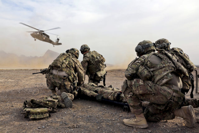 Modern military medic team prepare to move a simulated casualty to the evac helicopter during a training exercise. 