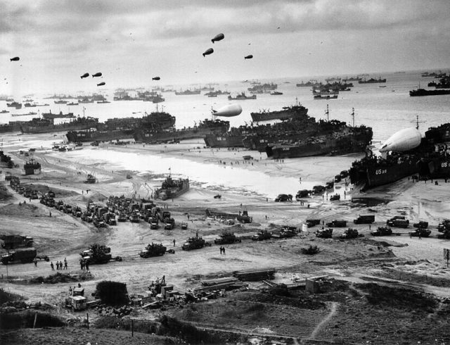 Landing ships putting cargo ashore on one of the invasion beaches during the Battle of Normandy. Note the barrage balloons;