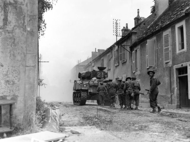 Canadian troops advance cautiously through the streets of Falaise, encountering only light scattered resistance.