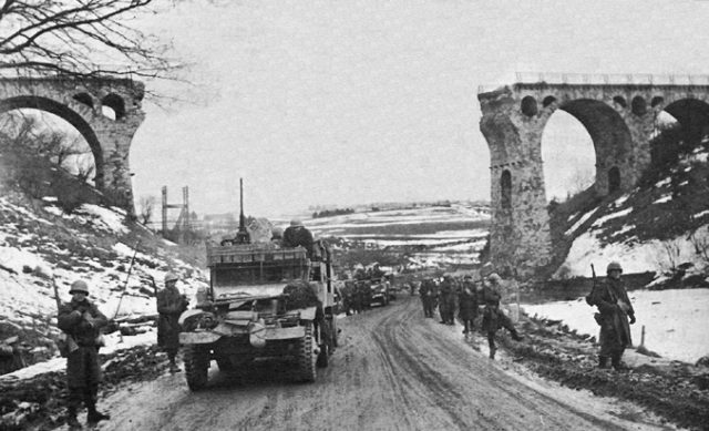 US troops passing through the railway viaduct north of Bütgenbach, Ardenes, Belgium.