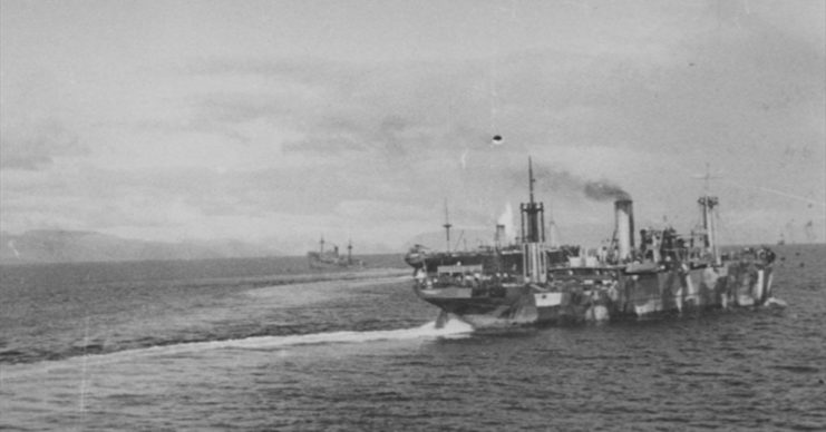 SLADEN’S TORPEDOES: A rare moment captured by a German soldier with his camera: a column of water shoots up from the German troopship Bahia Laura (hidden behind steamer) which has just been hit by torpedo number 2 from HMS Trident (submerged somewhere outside the left side of the picture), while Donau II (in the distance in mid-picture) has been hit in the engine-room and will sink during the next six minutes. More than 600 German soldiers perished, and the fortunes of war changed.