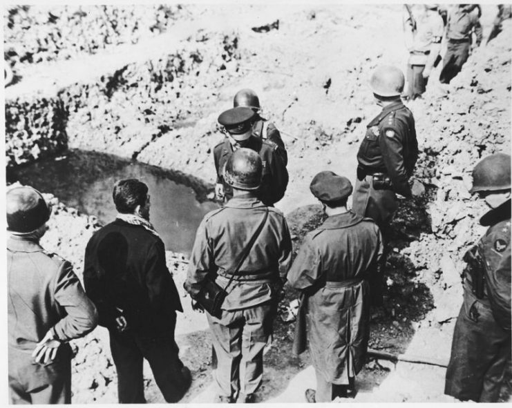 High-ranking U.S. Army officers examine a mass grave in the newly liberated Ohrdruf concentration camp. Among those pictured are Generals Dwight D. Eisenhower, George Patton, Omar Bradley and Manton Eddy. Also pictured is Jules Grad, correspondent for the U.S. Army newspaper, “Stars and Stripes”.