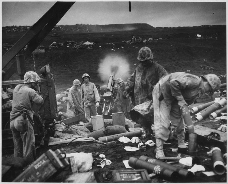 Across the litter on Iwo Jima’s black sands, Marines of the 4th Division shell Japanese positions, 1945