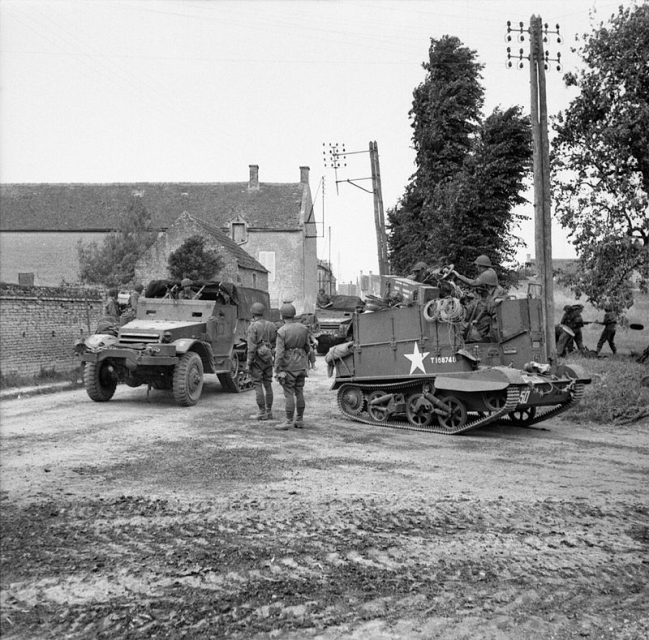 The British Army in Normandy 1944 A Universal carrier with wading screens attached and half-tracks passing through Hermanville-sur-Mer, 6 June 1944.
