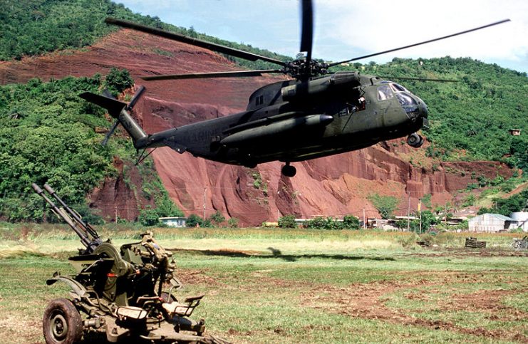 A U.S. Marine Corps Sikorsky CH-53D Sea Stallion helicopter hovers above the ground near a Soviet ZU-23 anti-aircraft weapon prior to picking it up during “Operation Urgent Fury”, the U.S. invasion of Grenada in October 1983.