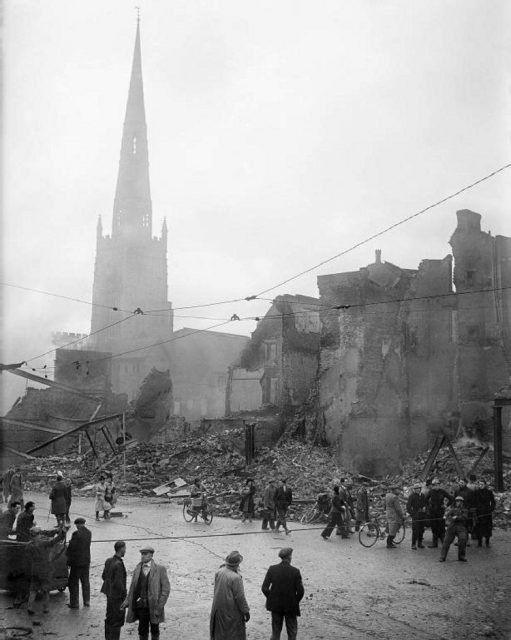 A street in Coventry, England, after the Coventry Blitz of November 14–15, 1940. In the background are the tower and spire of Holy Trinity parish church.