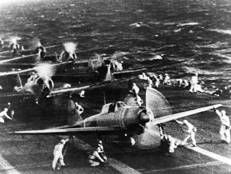 Japanese naval aircraft prepare to take off from an aircraft carrier (reportedly Shokaku) to attack Pearl Harbor during the morning of 7 December 1941. Plane in the foreground is a “Zero” Fighter, in front of “Val” dive bombers. This is probably the launch of the second attack wave.