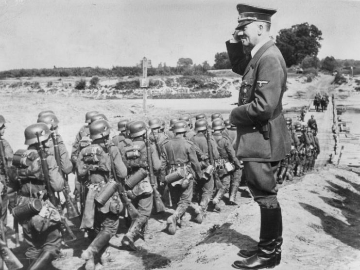 Adolf Hitler performing a military salute while he oversees marching Wehrmacht, September 1939.