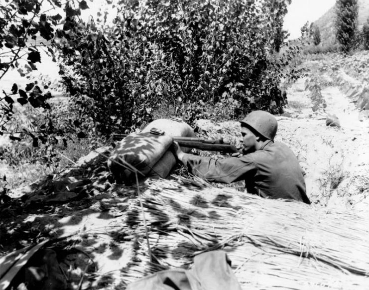Pfc. Letcher V. Gardner (Montgomery, Iowa) 8th Cavalry, fires on an emplacement along the Naktong River, near Chingu. 13 August 1950.