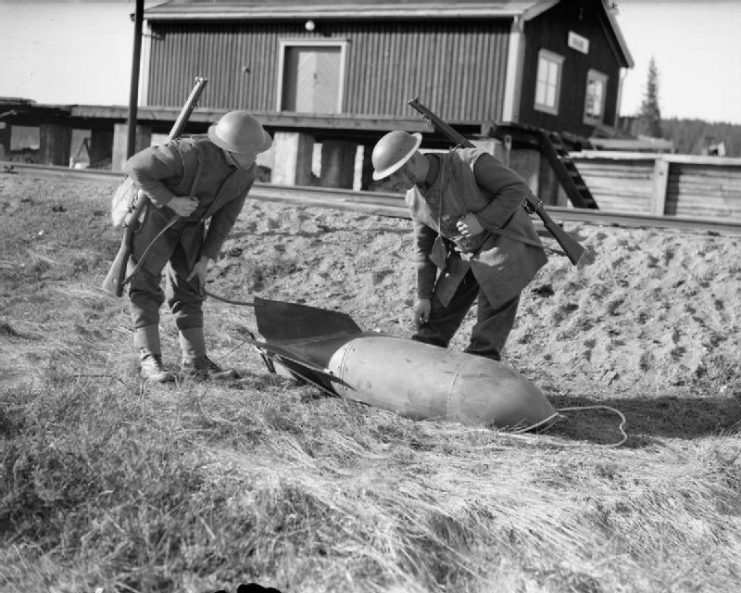 Troops examine an unexploded German bomb at the railway station at Grong, near Namsos, April 1940.