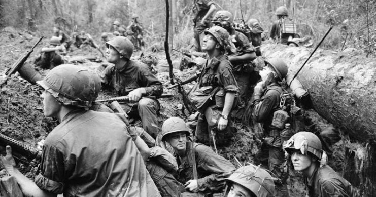 American infantrymen crowd into a mud-filled bomb crater and look up at tall jungle trees seeking out Viet Cong snipers firing at them during a battle in Phuoc Vinh, north-Northeast of Saigon in Vietnam’s War Zone D. Photo: manhhai CC BY 2.0