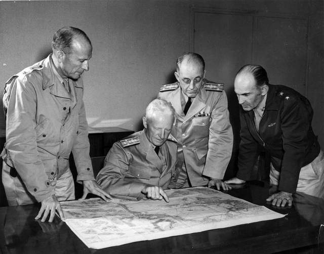 Admiral Nimitz (seated) discussing strategies in the South Pacific theater with top officers. 