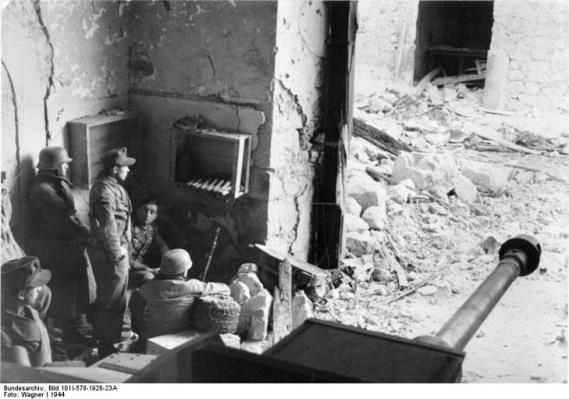 German paratroopers in a destroyed building in Monte Cassino. Sitting without a hat or helmet is Hauptmann Rudolf Rennecke. On the right a   Sturmgeschütz; PK Fs. AOK