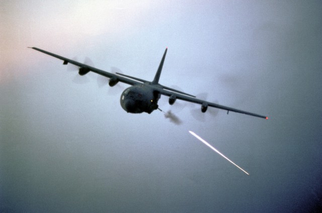 An air-to-air left front view of an AC-130 Hercules aircraft during target practice.