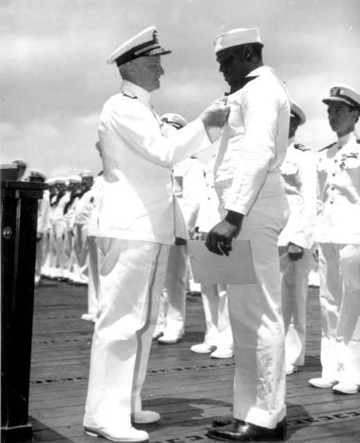 Chester W. Nimitz pins the Navy Cross on Doris Miller, at ceremony on board USS Enterprise (CV-6) at Pearl Harbor, May 27, 1942.