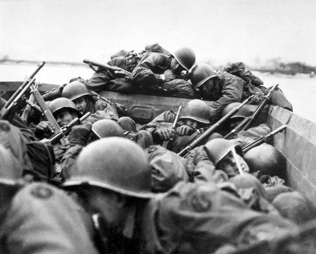 Men of the U.S. 89th Infantry Division cross the Rhine River in assault boats under German fire.