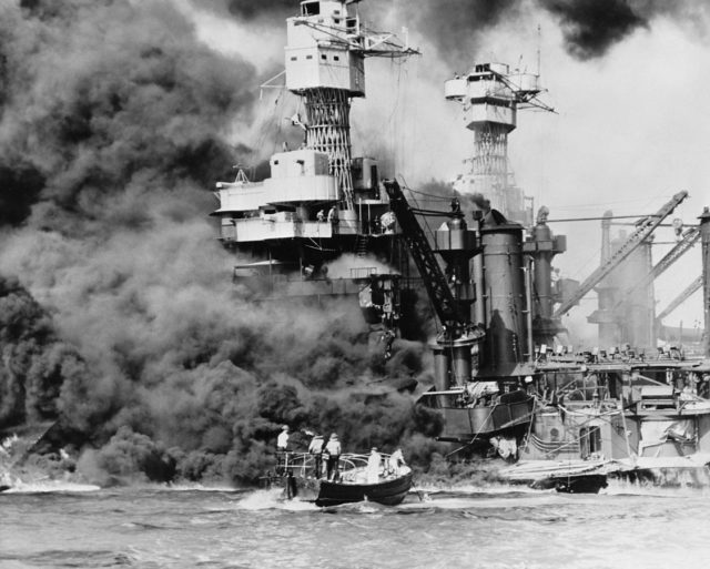 Sailors in a motor launch rescue a man overboard alongside the burning West Virginia during, or shortly after, the Japanese air raid on Pearl Harbor.