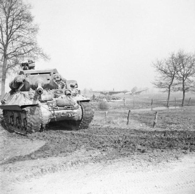  Achilles tank destroyer on the east bank of the Rhine moves up to link with airborne forces whose abandoned gliders can be seen in the background.