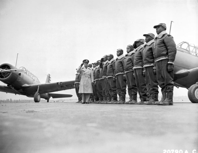 Major James A. Ellison returns the salute of Mac Ross, as he reviews the first class of Tuskegee cadets; flight line at U.S. Army Air Corps basic and advanced flying school, with Vultee BT-13 trainers in the background, Tuskegee, Alabama, 1941.