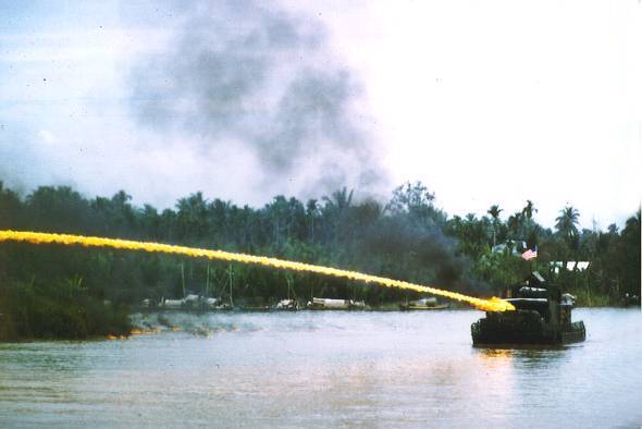 Riverboat of the U.S. Brown-water navy deploying an ignited napalm mixture from a riverboat mounted flamethrower in Vietnam. Public Domain. 