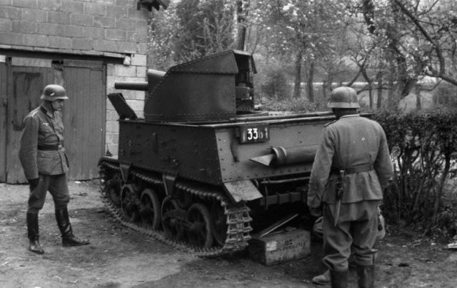 An abandoned Belgian T-13 tank destroyer is inspected by German soldiers. Photo Credit.