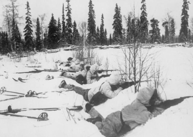 A Finnish ski patrol, lying in the snow on the outskirts of a wood in Northern Finland, on the alert for Russian troops, 12 January 1940.