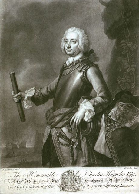 Commodore Charles Knowles in armour, one hand gestures to fortifications and a burning ship.