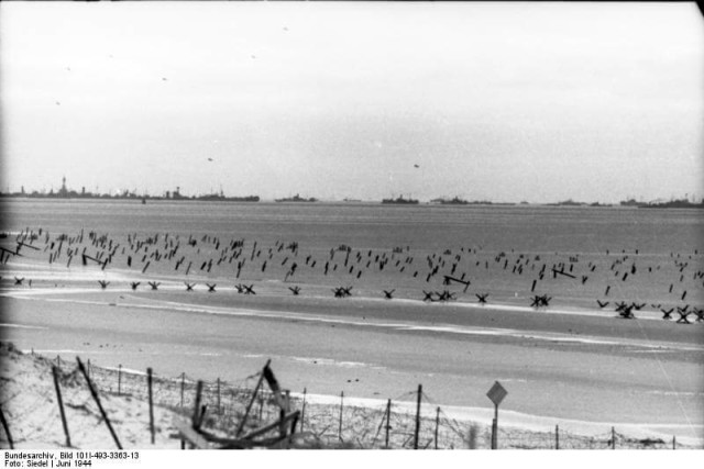 Beach fortifications with barber wire and tank traps. Northern France, 1944 (Image).
