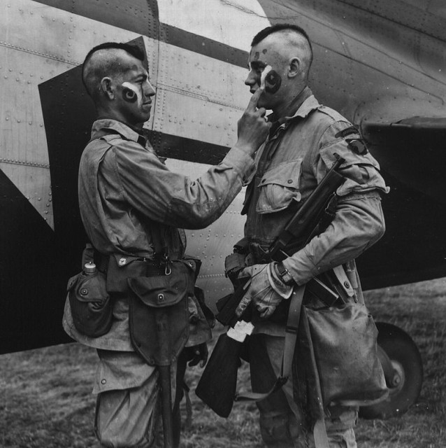 Private Ware applies last second war paint to Private Plaudo in England, June 1944 (Image)