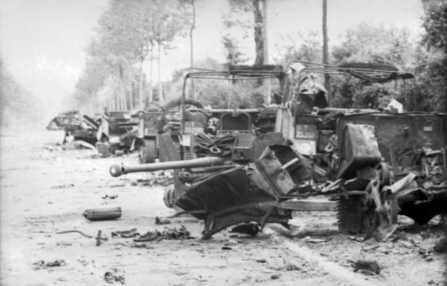 The wreckage of the 1st Rifle Brigade transport column and a 6-pounder anti-tank gun, on the road between Villers-Bocage and Point 213. By Bundesarchiv, CC-BY-SA 3.0, CC BY-SA 3.0 de.