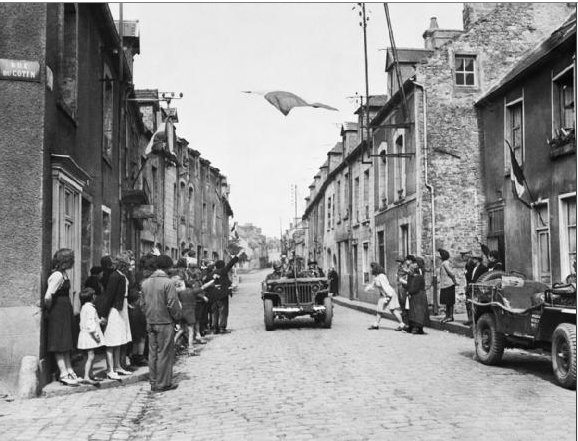 US Army jeep passes under the French flag as civilians thank the Americans after liberating the town. By US Army Signal Corps photographer - Imperial War Museum collection, http://www.iwm.org.uk/collections/item/object/205195375This is photograph EA 26383 from the collections of the Imperial War Museums., Public Domain.