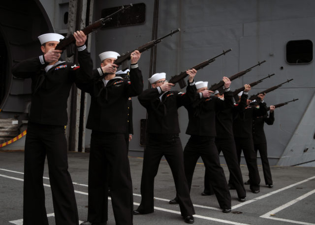 Sailors from the United States Navy form a rifle party and fire a volley salute on the deck of the aircraft carrier USS Abraham Lincoln during a burial at sea ceremony [U.S. Navy photo by Mass Communication Specialist Seaman Apprentice Aaron Hubner/Released]