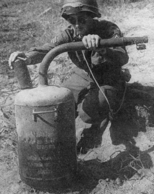 A US soldier holds up a German static flamethrower Abwehrflammenwerfer 42 [Via]