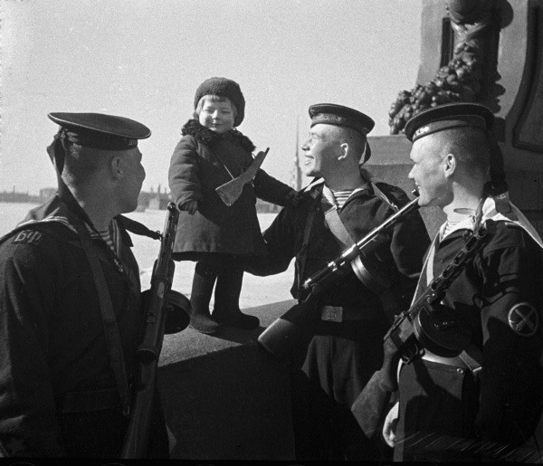 Baltic Fleet sailors with little girl Lucy, whose parents died in the siege. Russia, Leningrad [RIA Novosti archive, image # 393 / Boris Kudoyarov / CC-BY-SA 3.0]