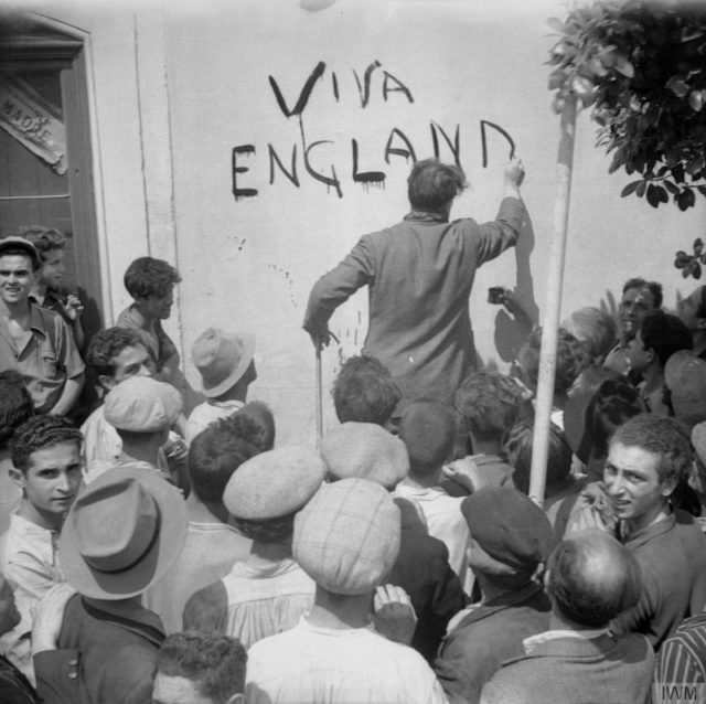Civilian resident of Misterbianco, near Catania, paints the slogan 'Viva England' on a wall after the village had been occupied by the Eighth Army. [© IWM (NA 5450)]