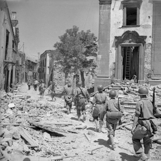 American troops advance through a damaged street in Randazzo. [© IWM (NA 5893)]