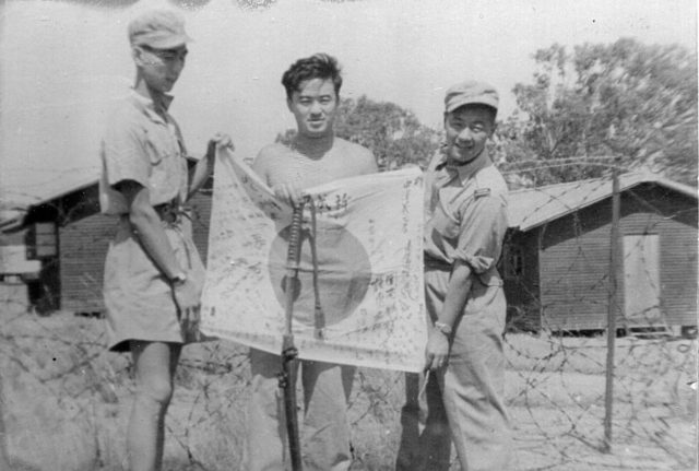 A few of the Force 136 members based out of Australia pose with a Japanese sword and flag.