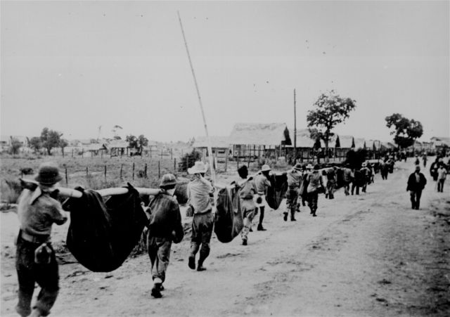 A burial detail of Filipino and prisoners of war uses improvised litters to carry fallen comrades at Camp O'Donnell, Capas, Tarlac, 1942, following the Bataan Death March.