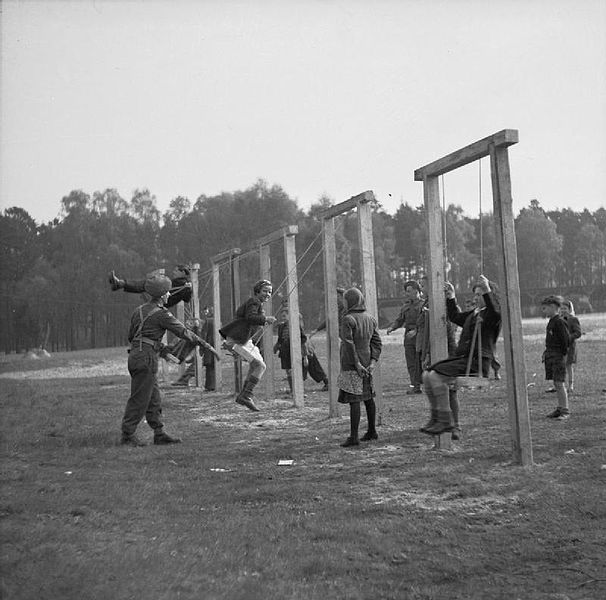 Children playing on swings erected by British soldiers at the Bergen-Belsen displaced persons camp after liberation. Wikimedia Commons / Public Domain. 