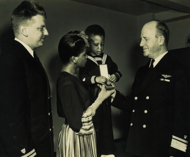 Kathleen David, widow to Charles, recieving the Navy and Marine Corps medal from USCG Rear Admiral. Lt. Anderson is on the far left. Image Source: Wikimedia Commons/ public domain