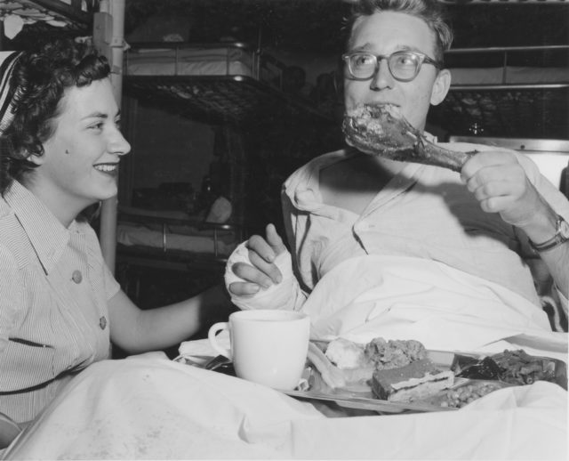 Inchon, Korea: Aboard USS Repose Thanksgiving Day. Corporal Richard R. Hollander, U.S. Marine Corps, is assisted with his dinner by Lieutenant Junior Grade Caldie Green (Nurse Corps) U.S. Navy.