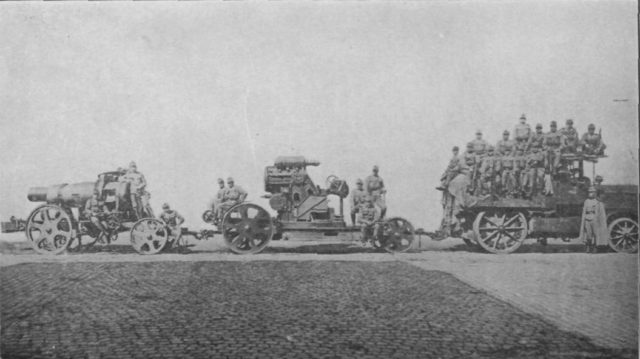 Barrel, body and crew towed by a motor tractor, circa. 1914.